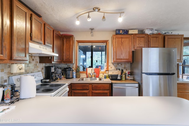 kitchen featuring backsplash, sink, stainless steel appliances, and a textured ceiling