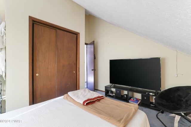 bedroom featuring a closet, a textured ceiling, and vaulted ceiling