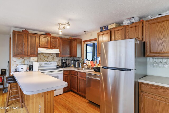 kitchen with sink, kitchen peninsula, a breakfast bar area, decorative backsplash, and appliances with stainless steel finishes