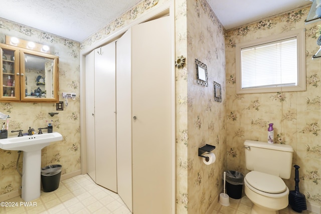 bathroom featuring a textured ceiling, toilet, and sink