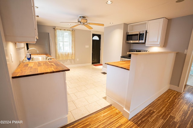 kitchen featuring ceiling fan, sink, wooden counters, white cabinets, and appliances with stainless steel finishes