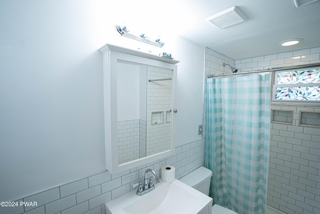 bathroom with vanity, tile walls, and toilet