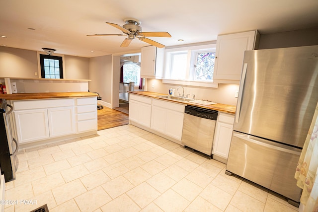 kitchen featuring wood counters, stainless steel appliances, ceiling fan, sink, and white cabinets