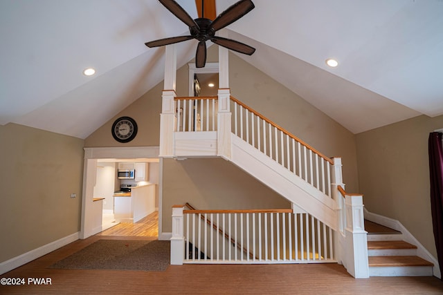 staircase with ceiling fan, hardwood / wood-style floors, and lofted ceiling