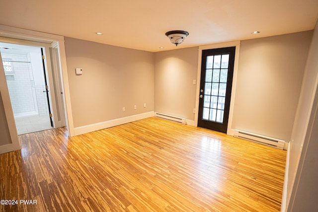 empty room with light wood-type flooring and a baseboard radiator