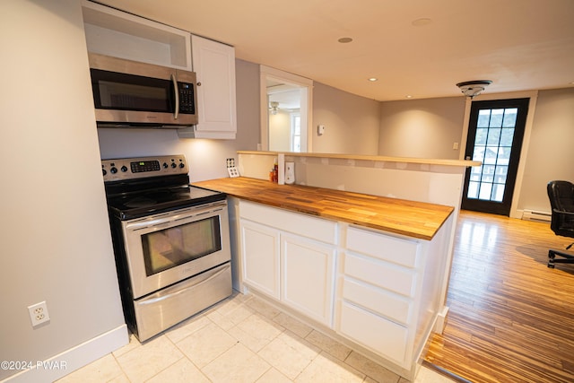 kitchen with white cabinetry, stainless steel appliances, a baseboard radiator, butcher block countertops, and kitchen peninsula