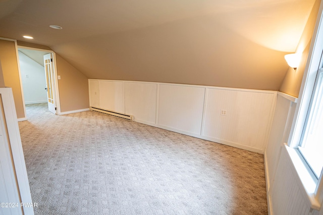 additional living space with vaulted ceiling, light carpet, and a baseboard heating unit