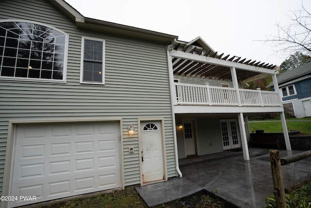 rear view of property featuring french doors, a balcony, and a garage