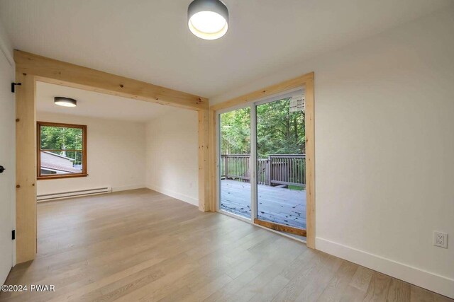 empty room with baseboard heating, beamed ceiling, and light wood-type flooring