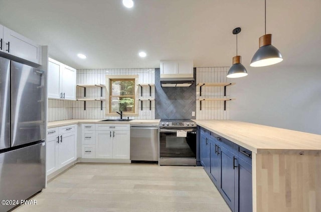 kitchen with appliances with stainless steel finishes, backsplash, sink, white cabinets, and hanging light fixtures