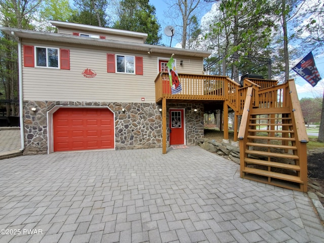view of front of home featuring an attached garage, decorative driveway, stairway, and stone siding
