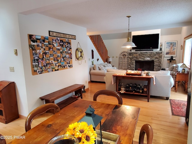 dining room with a fireplace, light hardwood / wood-style floors, and a textured ceiling