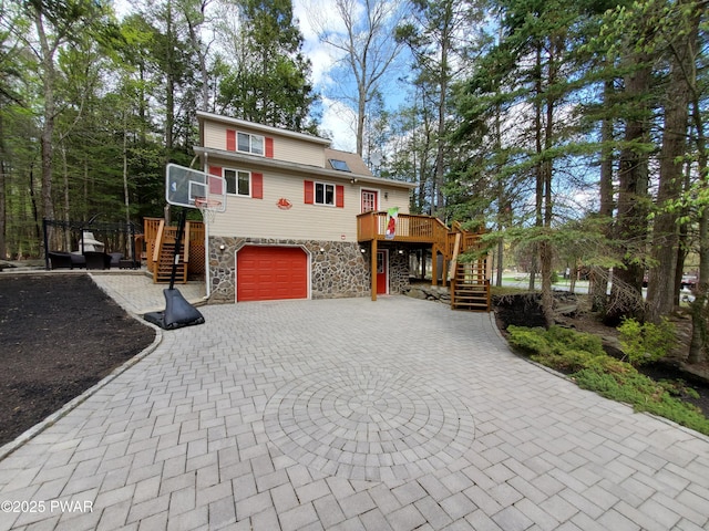 chalet / cabin featuring stone siding, a garage, a wooden deck, stairway, and curved driveway