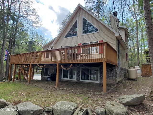 back of property with a chimney, stone siding, and a deck