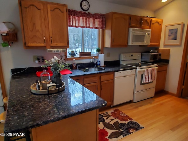 kitchen featuring white appliances, light hardwood / wood-style floors, sink, and dark stone countertops