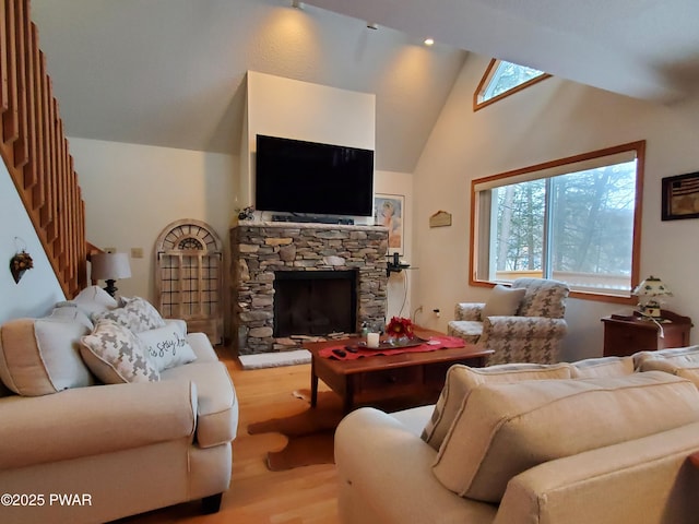 living room featuring wood-type flooring, a stone fireplace, and high vaulted ceiling