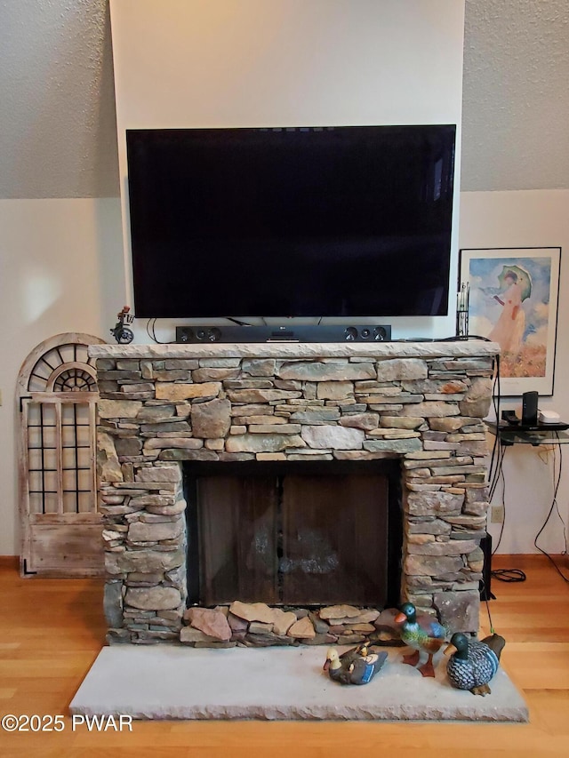 room details featuring wood-type flooring, a textured ceiling, and a fireplace