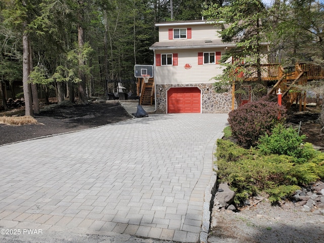 rustic home with stairs, decorative driveway, an attached garage, and stone siding