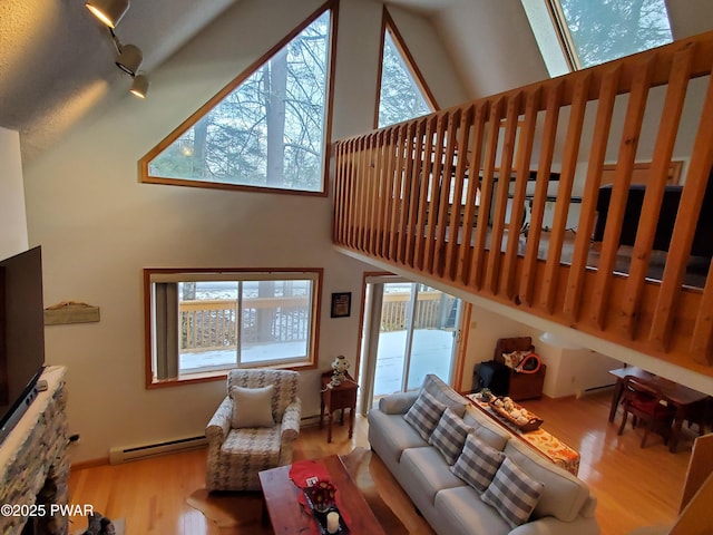 living room with high vaulted ceiling, a baseboard heating unit, rail lighting, and wood finished floors