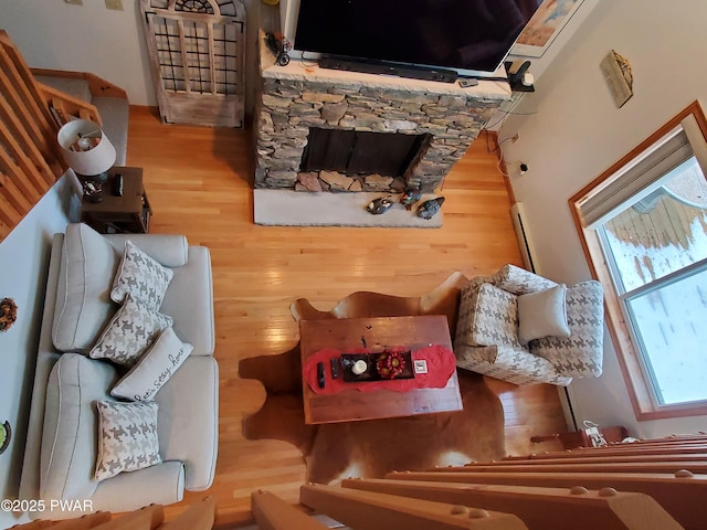 living room featuring wood-type flooring and a stone fireplace