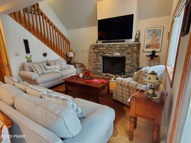 living room featuring hardwood / wood-style floors, a stone fireplace, and vaulted ceiling