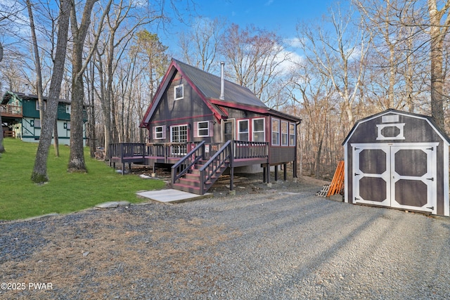 rustic home featuring a wooden deck, a storage unit, a front yard, and an outdoor structure