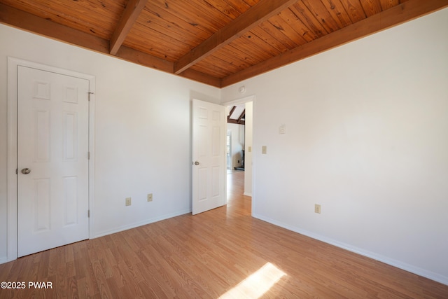 unfurnished bedroom featuring beam ceiling, light wood finished floors, wood ceiling, and baseboards