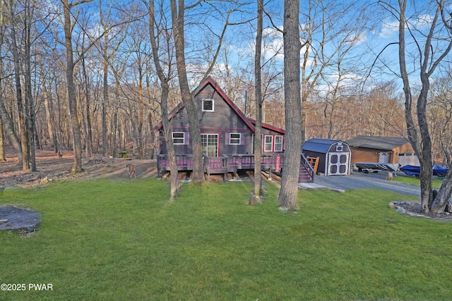 view of front of property featuring an outbuilding, a deck, a storage unit, and a front lawn