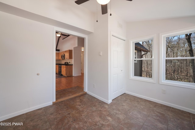 spare room featuring vaulted ceiling, baseboards, visible vents, and ceiling fan