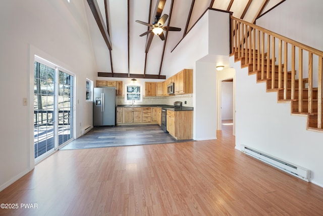 kitchen featuring baseboard heating, stainless steel appliances, ceiling fan, and wood finished floors