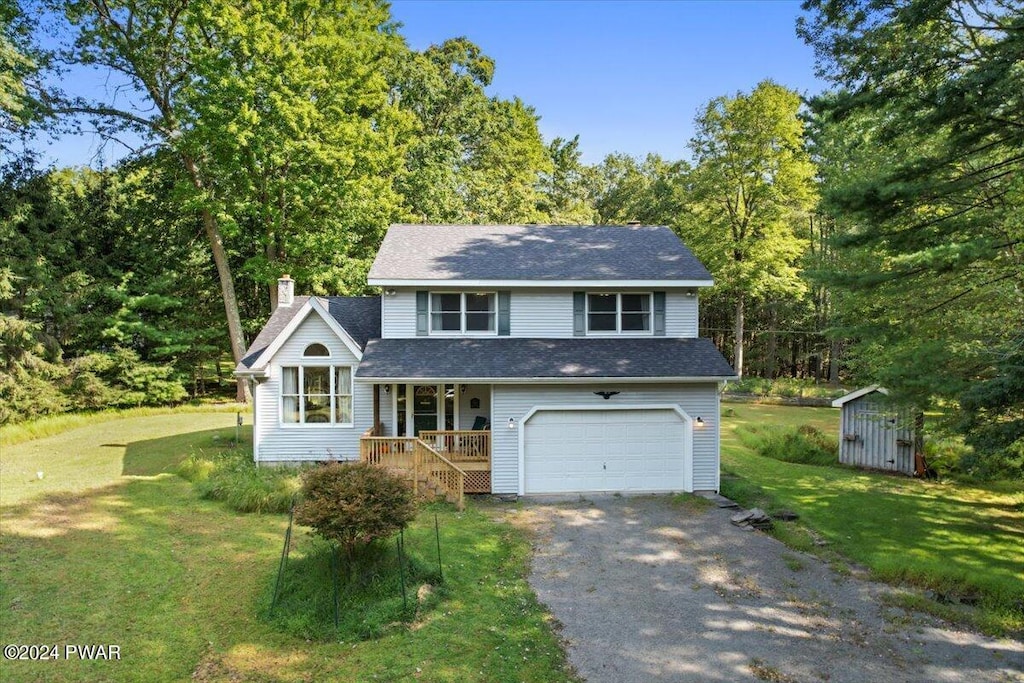 view of front facade featuring a front yard, a garage, a storage unit, and covered porch