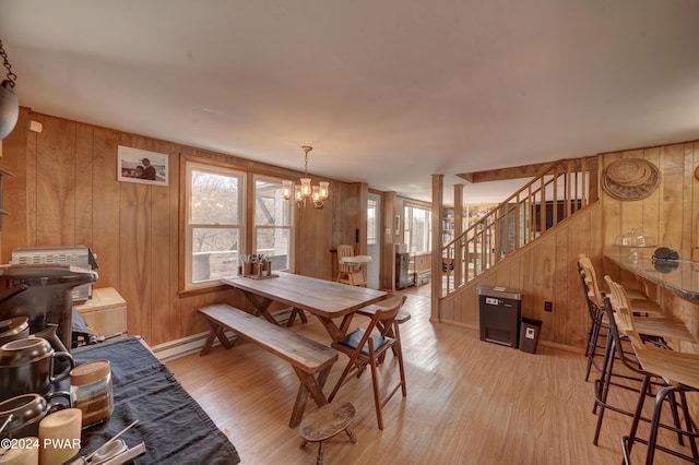 dining area featuring wood walls, light hardwood / wood-style floors, and a chandelier