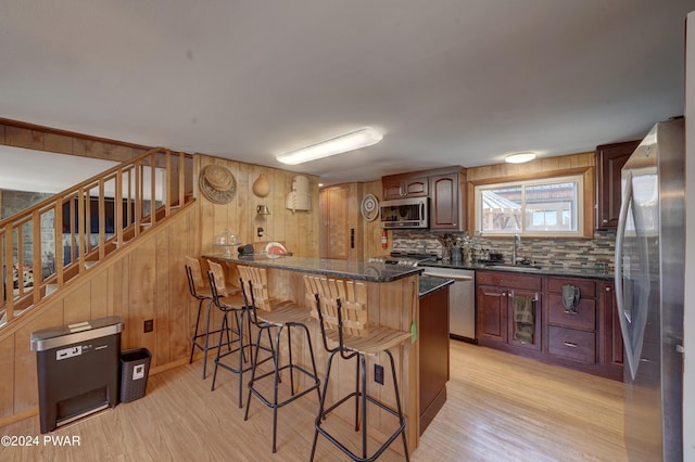 kitchen featuring a breakfast bar, light hardwood / wood-style floors, sink, and appliances with stainless steel finishes