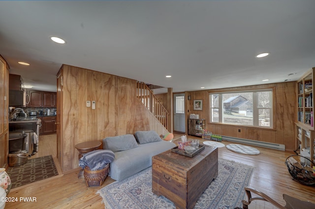 living room with wood walls, light wood-type flooring, and a baseboard heating unit