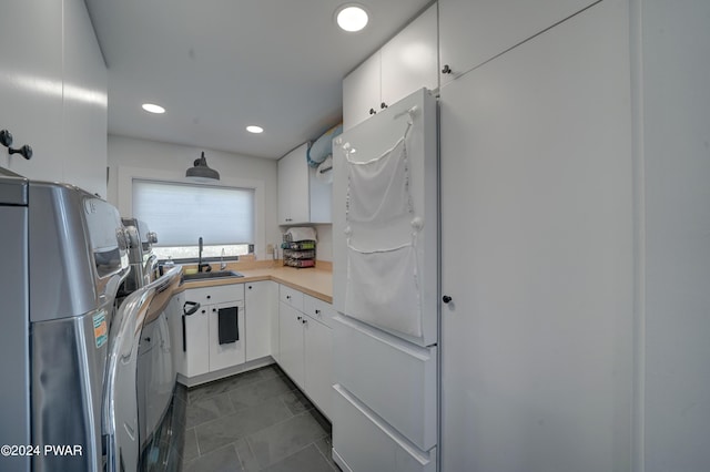 kitchen featuring dark tile patterned flooring, white refrigerator, white cabinetry, and sink