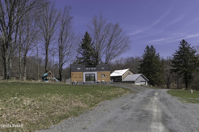 view of front of house featuring a lawn, a playground, a garage, and an outdoor structure