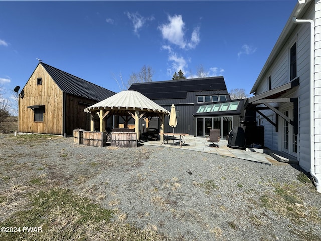 rear view of property with a gazebo, a bar, a patio, and solar panels