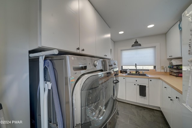 clothes washing area featuring cabinets, washing machine and dryer, and sink