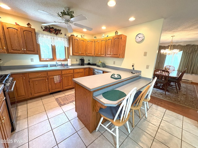 kitchen with a sink, appliances with stainless steel finishes, a breakfast bar area, a peninsula, and a chandelier