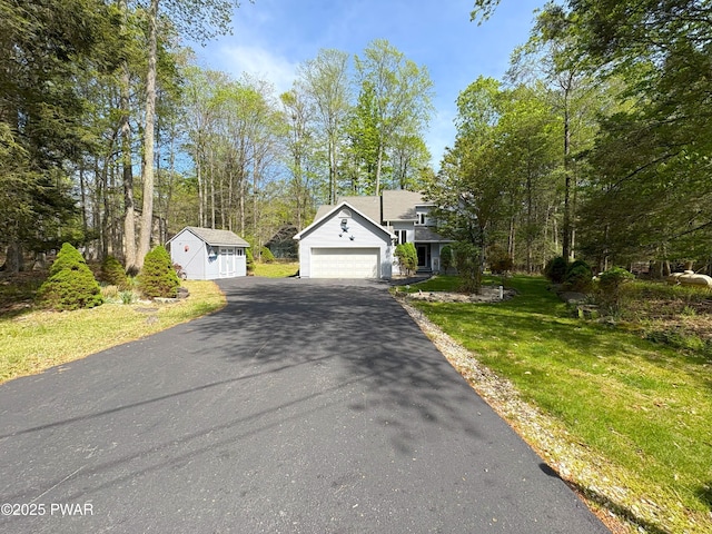 view of front facade featuring driveway, a front lawn, and an outbuilding