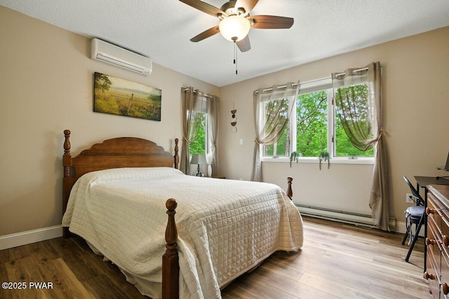 202 Remuda Dr, Lords Valley, PA 18428 - bedroom featuring a wall mounted AC, a baseboard heating unit, wood finished floors, and a ceiling fan