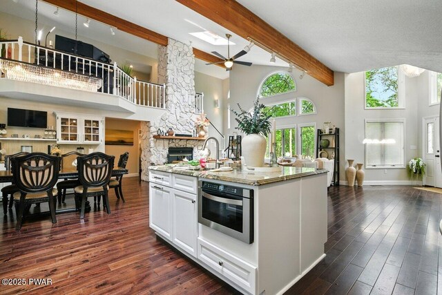 202 Remuda Dr, Lords Valley, PA 18428 - kitchen with open floor plan, a high ceiling, beam ceiling, light stone counters, and white cabinetry