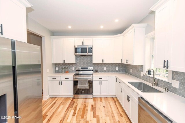 209 Conashaugh Trl, Milford, PA 18337 - kitchen with stainless steel appliances, light wood-style floors, white cabinetry, light countertops, and backsplash