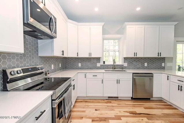 209 Conashaugh Trl, Milford, PA 18337 - kitchen with stainless steel appliances, white cabinetry, light wood-type flooring, light countertops, and backsplash
