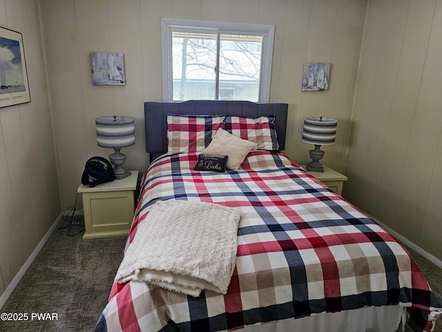 bedroom with dark colored carpet and wooden walls