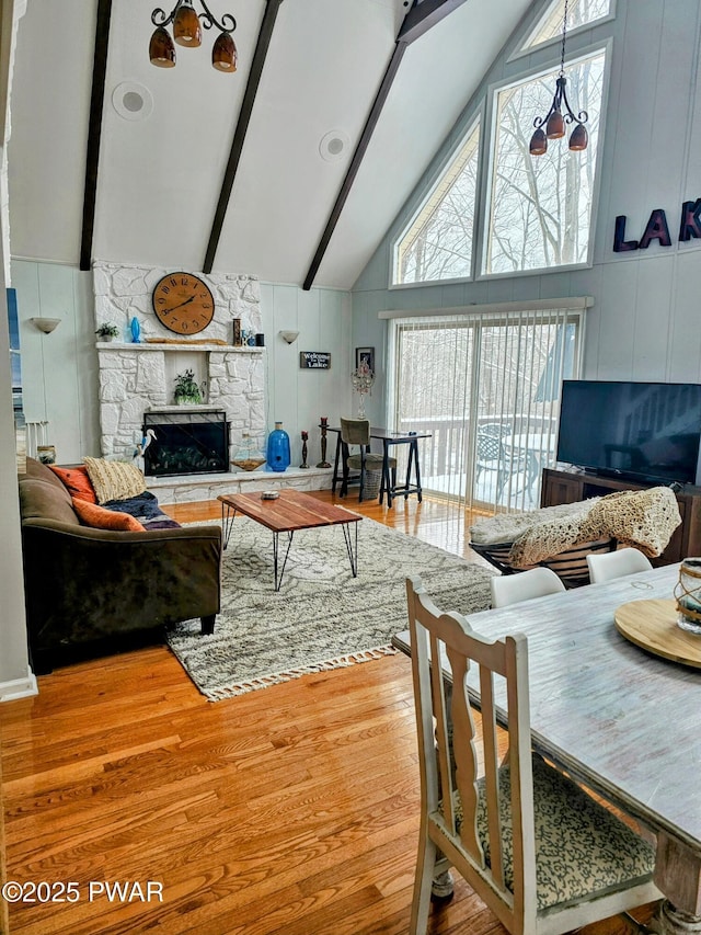 living room with beam ceiling, an inviting chandelier, high vaulted ceiling, a fireplace, and hardwood / wood-style flooring