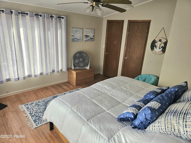 bedroom with two closets, crown molding, vaulted ceiling, ceiling fan, and wood-type flooring