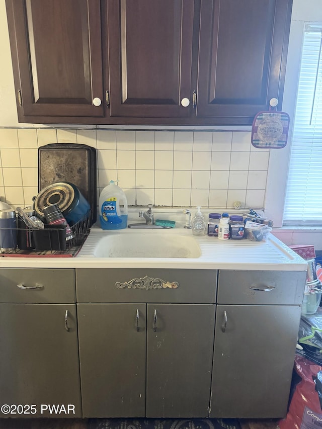 kitchen with dark brown cabinetry, sink, and backsplash