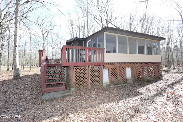 back of property with a wooden deck and a sunroom