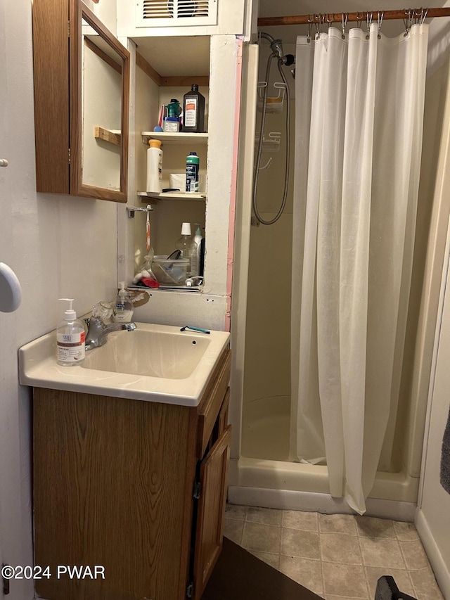 bathroom featuring tile patterned flooring, vanity, and curtained shower